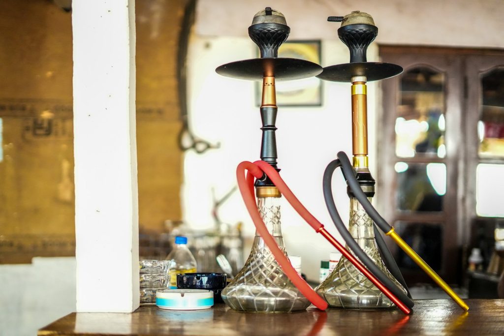 Two ornate hookahs with red and black hoses
